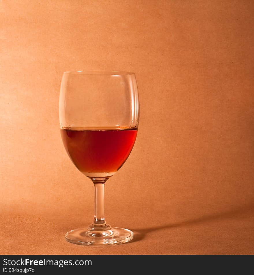 Elegant red wine glass on brown wooden background