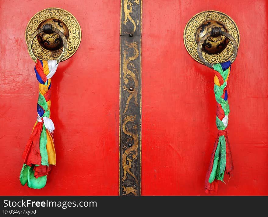 Typical Tibetan red doors with doorring and prayer flags. Typical Tibetan red doors with doorring and prayer flags