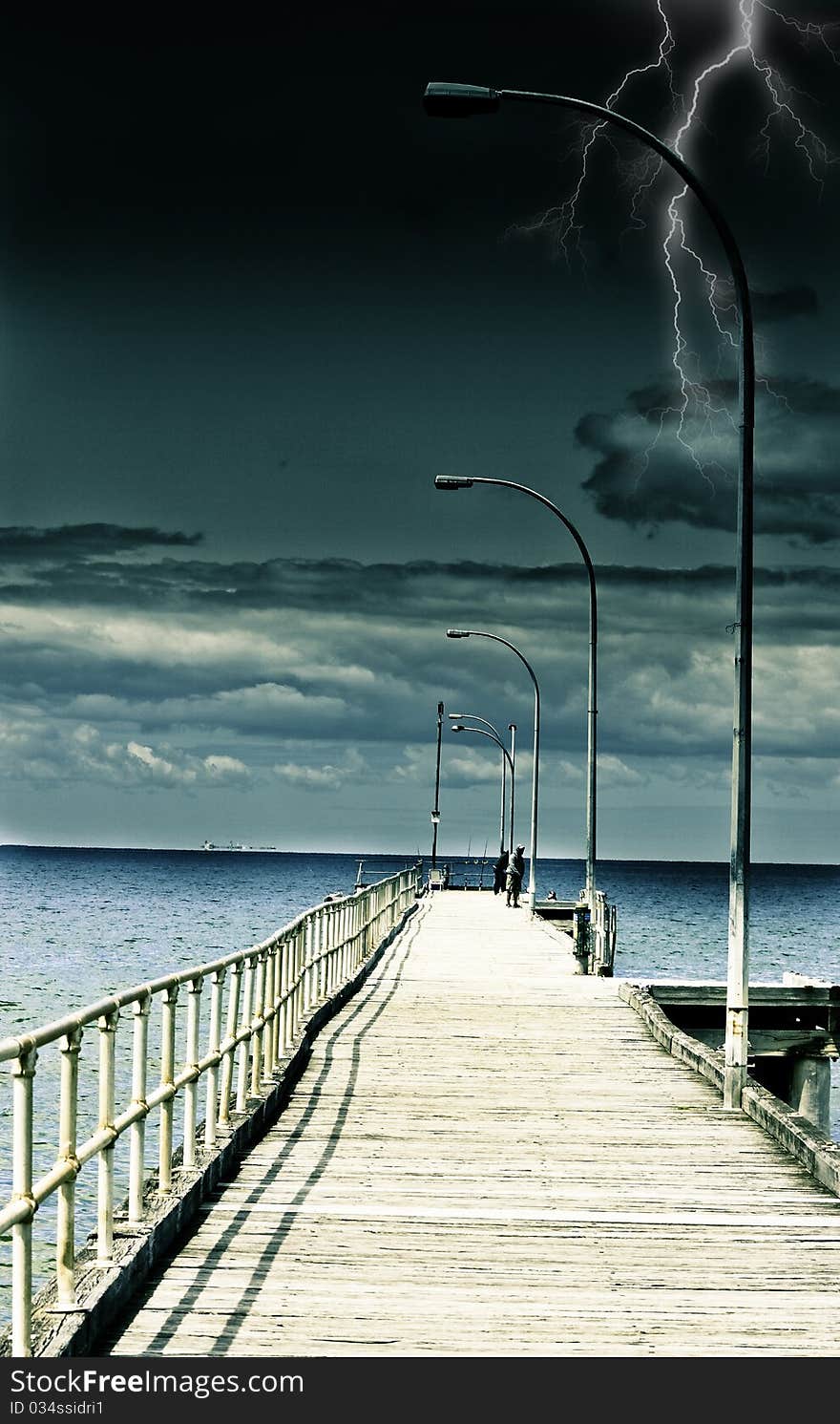 Early evening and lightning is starting in the background looking down the pier blue waters. Early evening and lightning is starting in the background looking down the pier blue waters