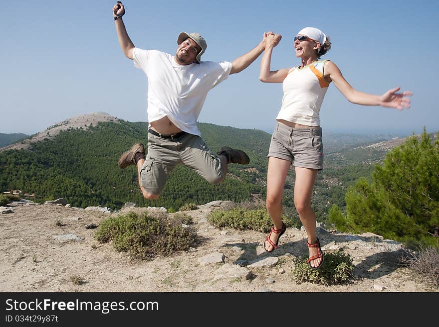 Funny young couple jumping in mountains