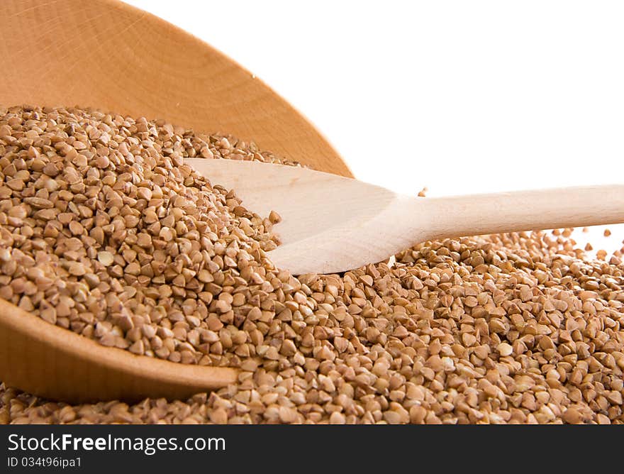 Buckwheat and wooden spoon on white