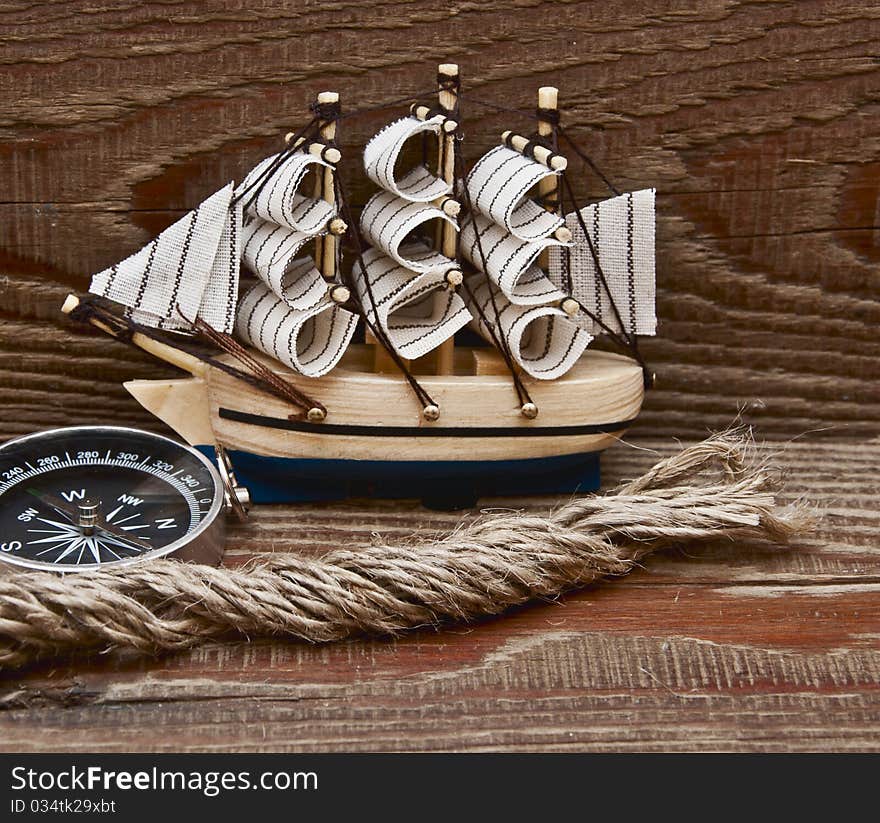 Compass, rope and model classic boat on wood background