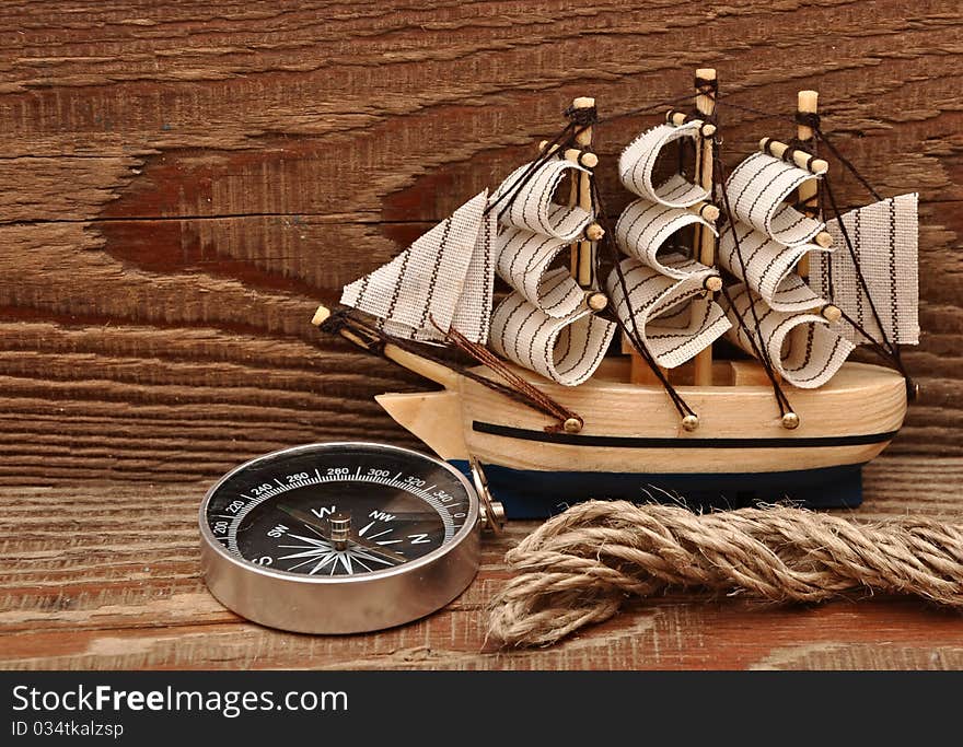 Compass, rope and model classic boat on wood background