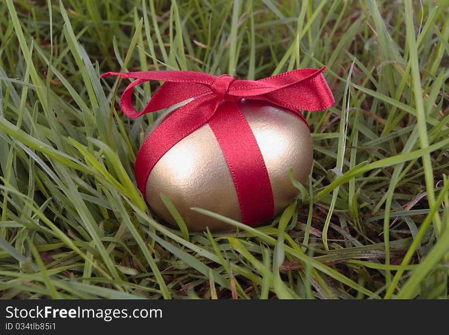 Gold easter egg and ribbon on grass. Gold easter egg and ribbon on grass