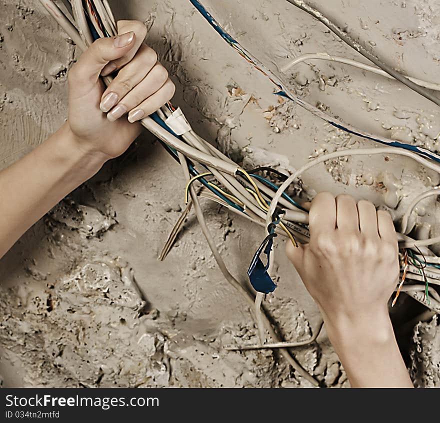 Woman hands grabbing wires to tear it on concrete wall background