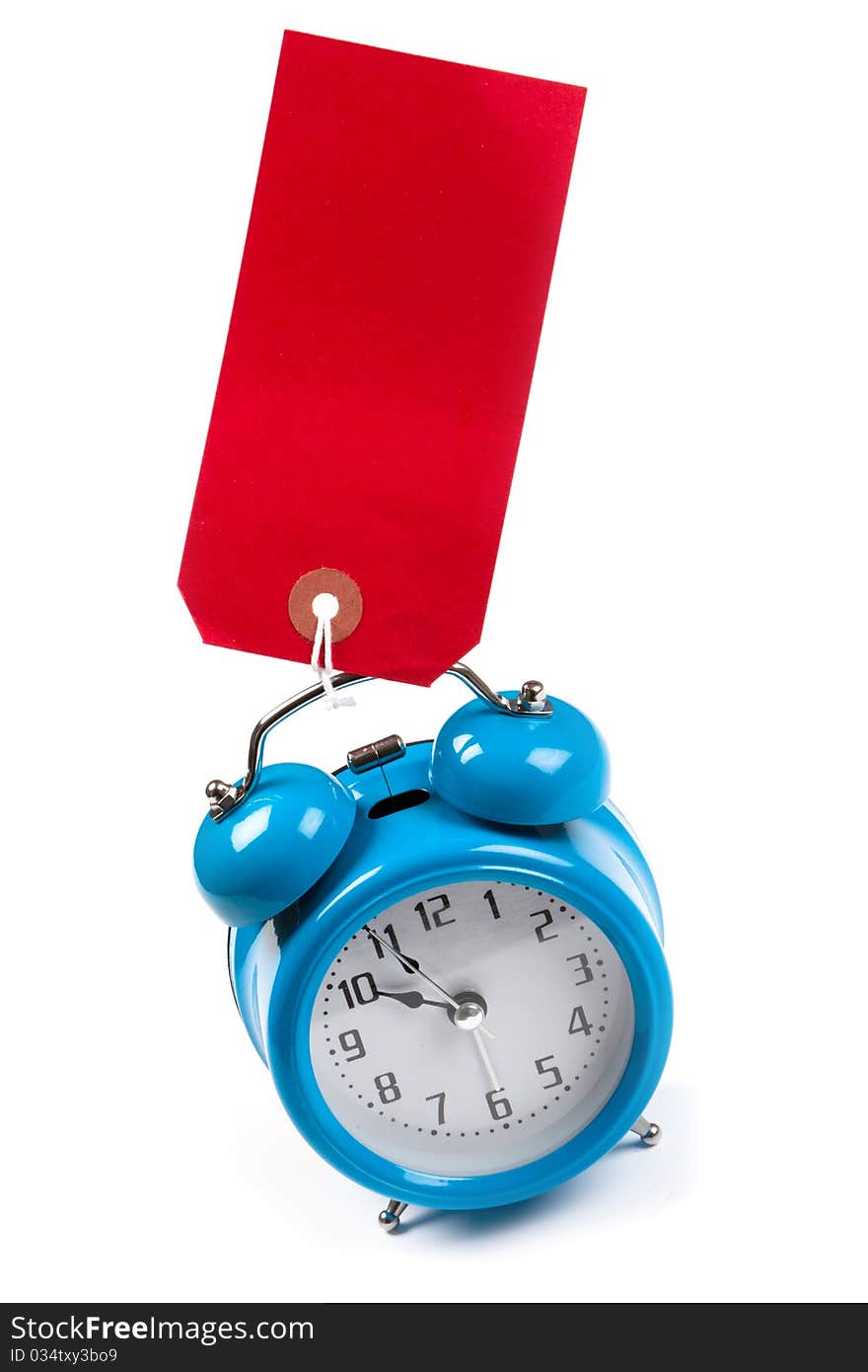 Blue alarm clock with a blank red luggage tag stuck to. Blue alarm clock with a blank red luggage tag stuck to