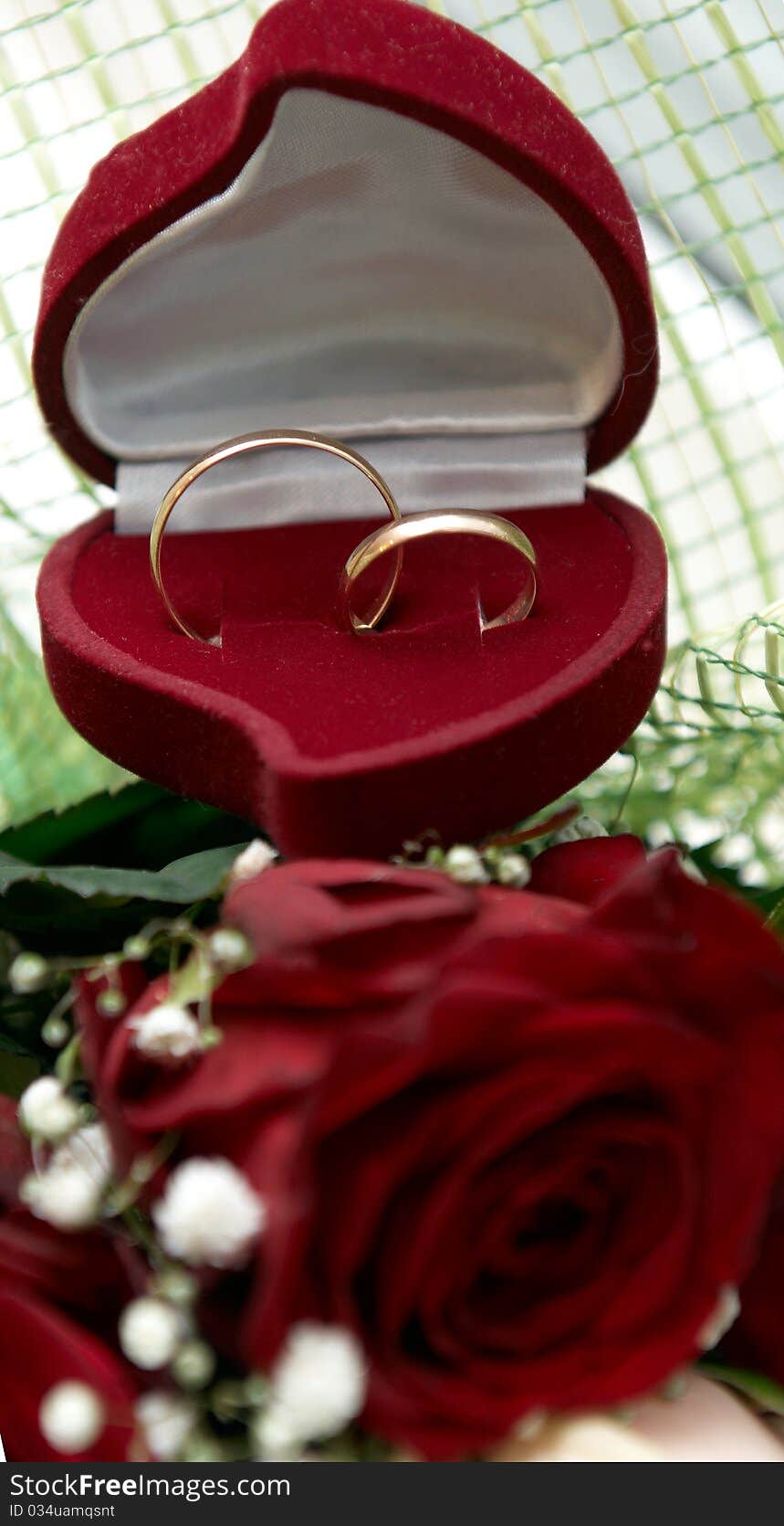 Wedding rings on bouquet of red roses