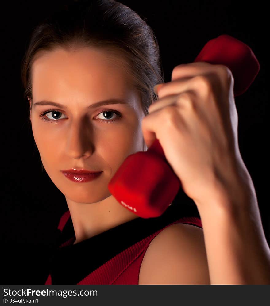 Confident woman athlete shows red dumbbell in her hand. Confident woman athlete shows red dumbbell in her hand