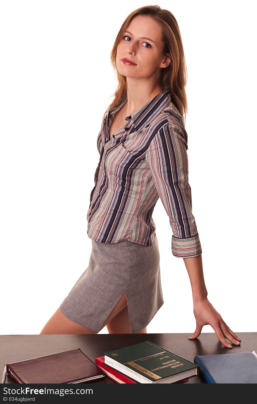 Beautiful woman teacher standing at the desk with books on top of it