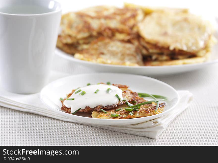 Potato pancakes on plate with sour cream