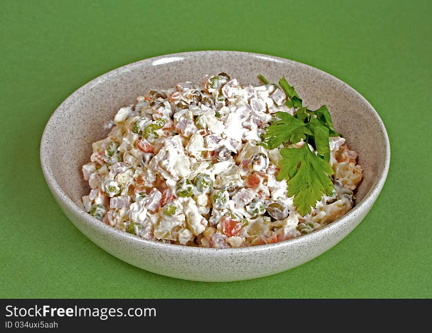 Traditional russian salad olivier in bowl on green background