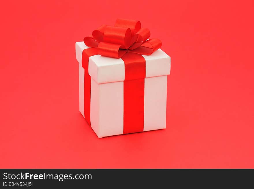 White gift box with a red bow on red background