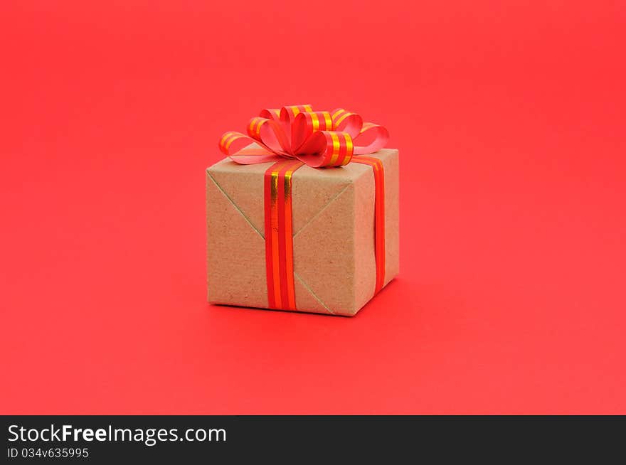 Gift box with gold and red ribbon in red background.