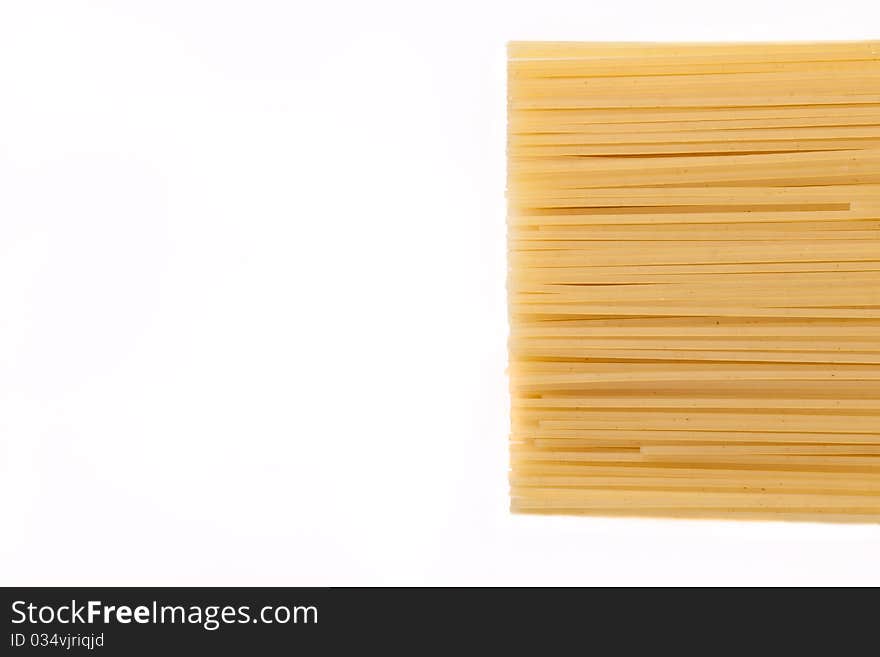 Spaghetti lie on a white background on the right side of the frame, the frame is horizontal. Spaghetti lie on a white background on the right side of the frame, the frame is horizontal