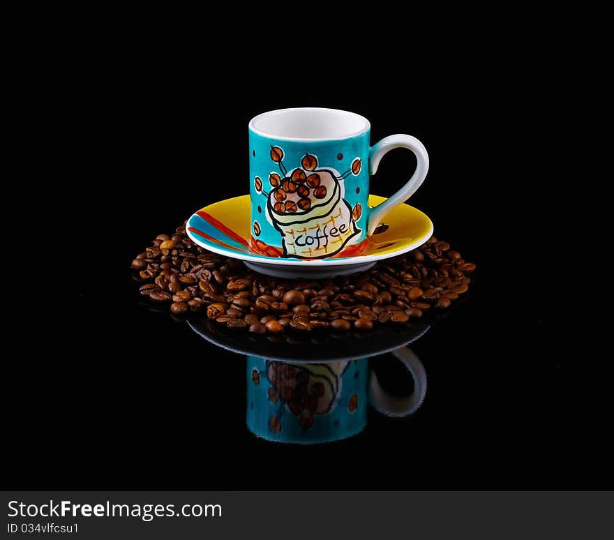 Illustrated turquoise coffee cup and saucer on roasted beans. Illustrated turquoise coffee cup and saucer on roasted beans