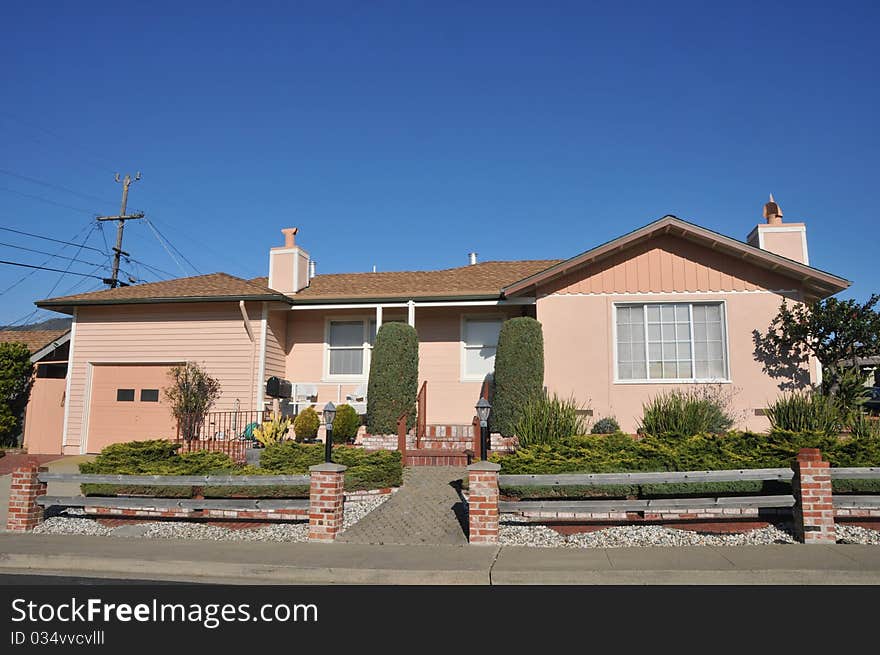 House surrounded by trees and grass with blue sky.