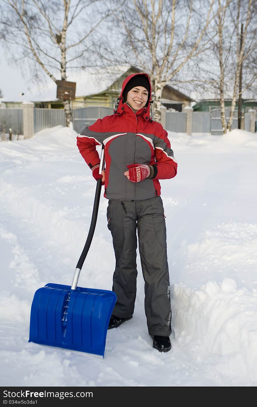 The girl in a winter sports jacket holds a shovel