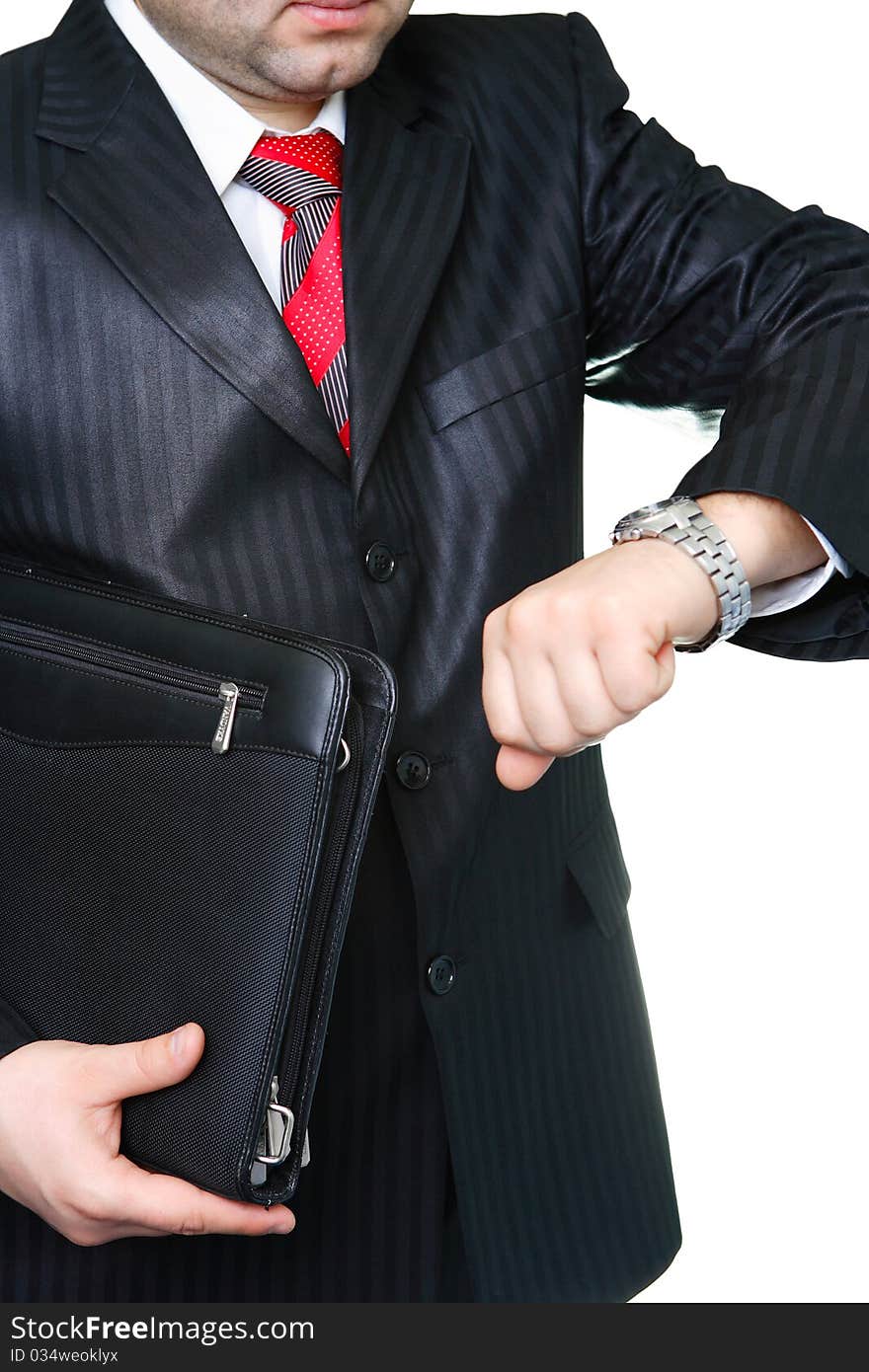 The businessman in a black suit with a portfolio looks at a watch. The businessman in a black suit with a portfolio looks at a watch