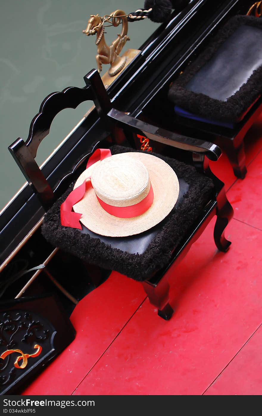 A close up shot from an elegant gondola seat with a gondolier’s straw-hat with red ribbon, Venice, Italy. A close up shot from an elegant gondola seat with a gondolier’s straw-hat with red ribbon, Venice, Italy