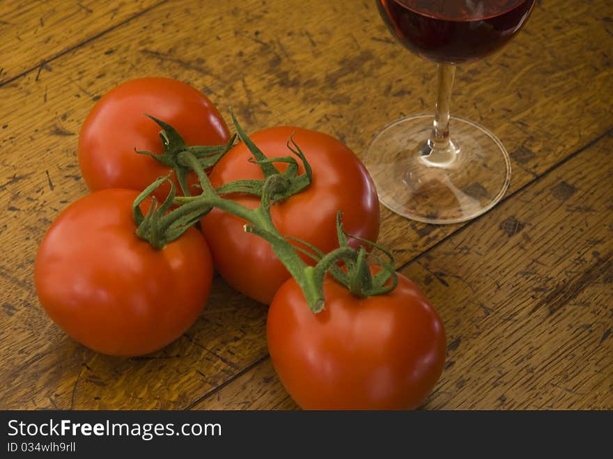 Tomatoes and a glass of red wine on an old wooden table