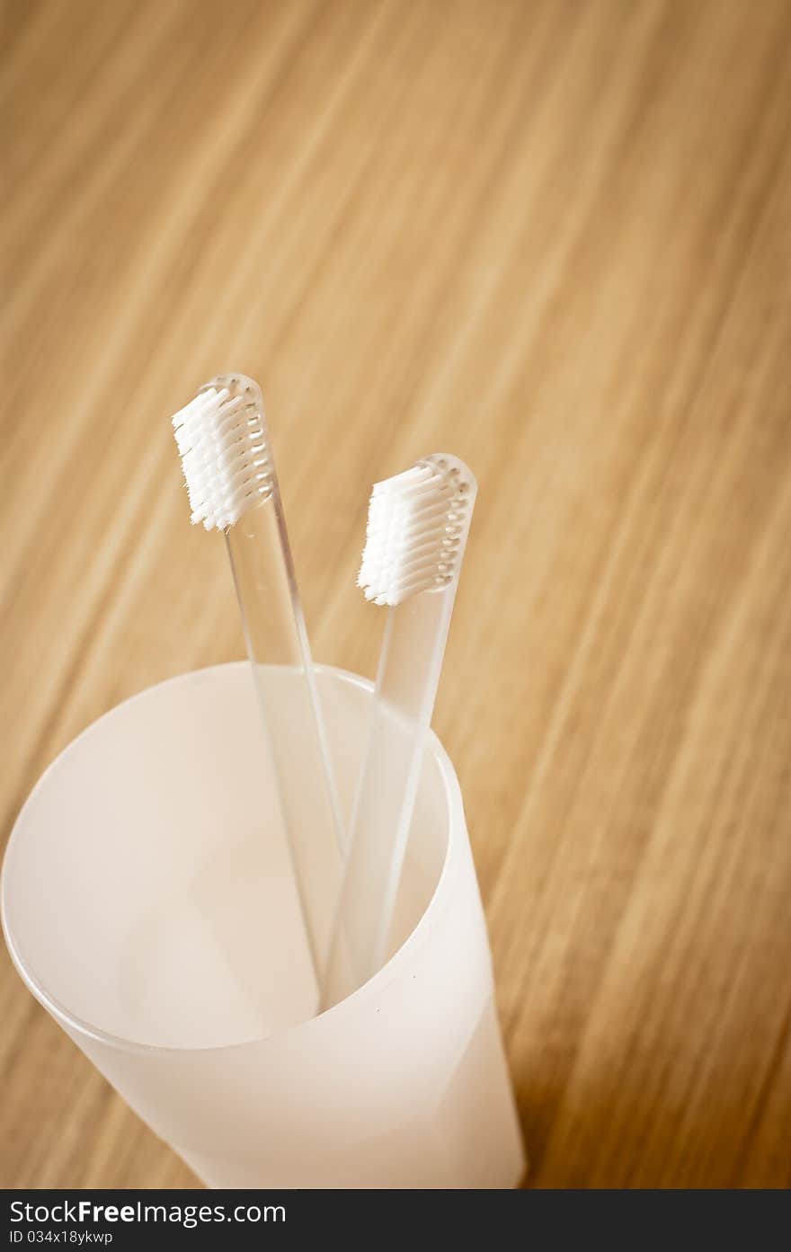 Toothbrush in glass on wood floor