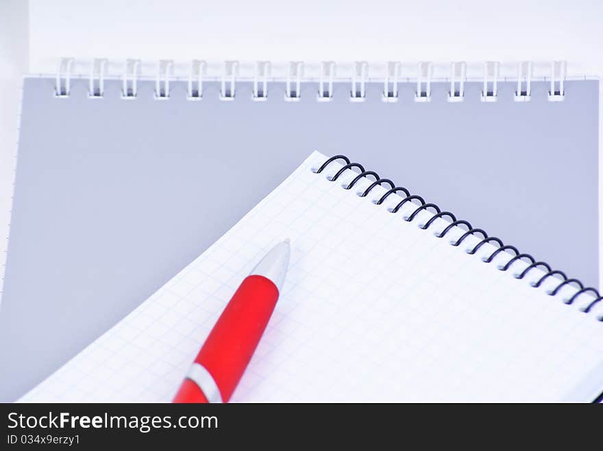 A red pen on a notebook, isolated in white background.