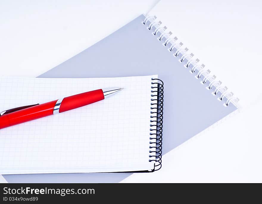 A red pen on a notebook, isolated in white background.