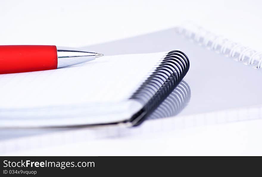 A red pen on a notebook, isolated in white background.