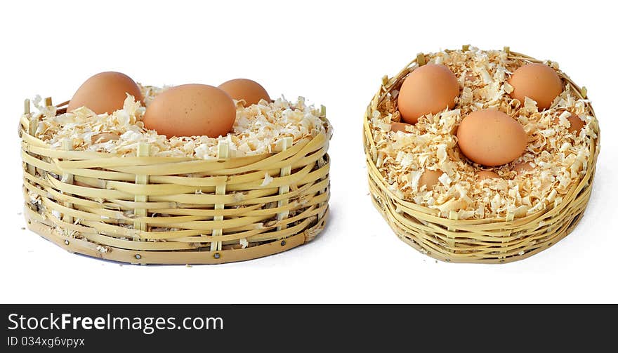 Three chicken eggs in a straw basket with wood shreds to remove humidity. Three chicken eggs in a straw basket with wood shreds to remove humidity.