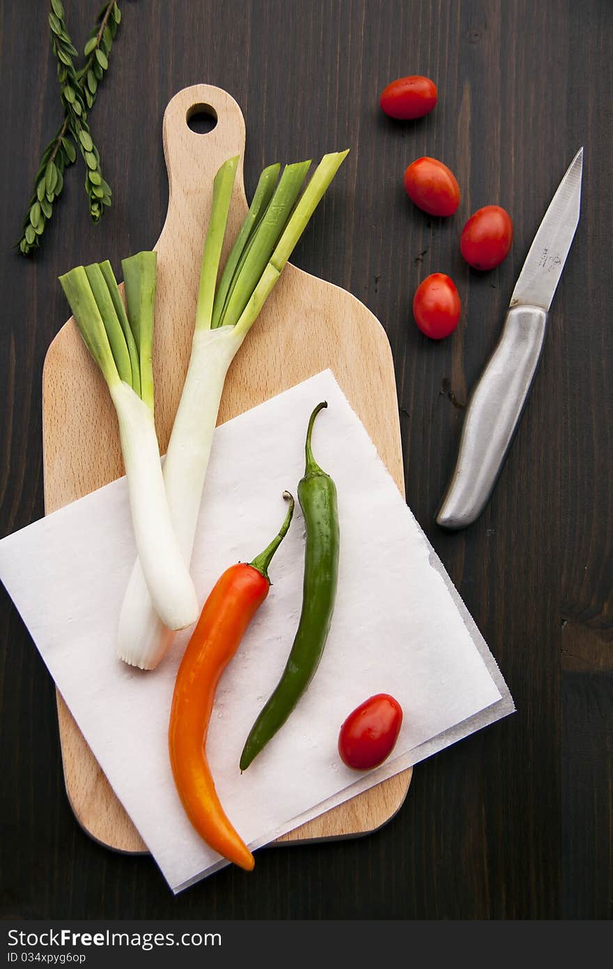 Fresh peppers and leeks on wooden background