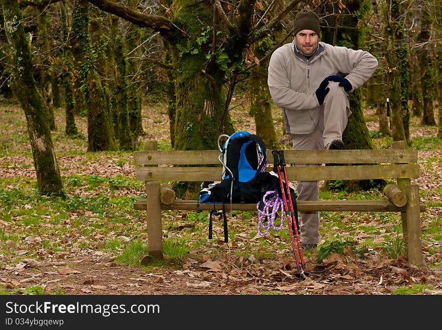 Hiker stretching with gear over a wood bench