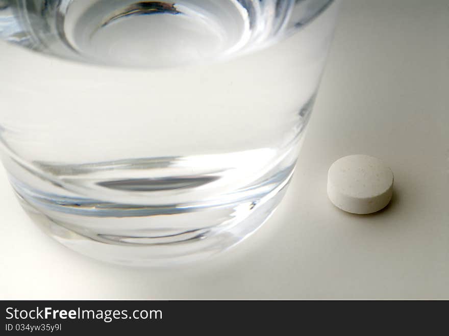 Pill next to a glass of water