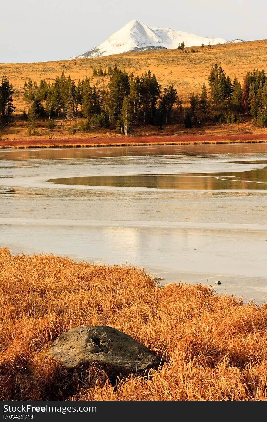 Snow capped mountain in Yellowstone sits behind the ice covered Swan Lake. Snow capped mountain in Yellowstone sits behind the ice covered Swan Lake.