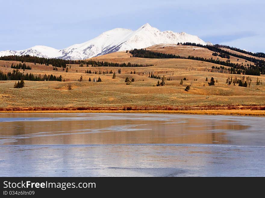 Thin layer of ice covers Swan Lake with a snow capped Electric Peak in the background, Yellowstone. Thin layer of ice covers Swan Lake with a snow capped Electric Peak in the background, Yellowstone.