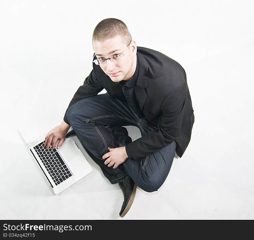 Young businessman in suit sitting on the floor with laptop