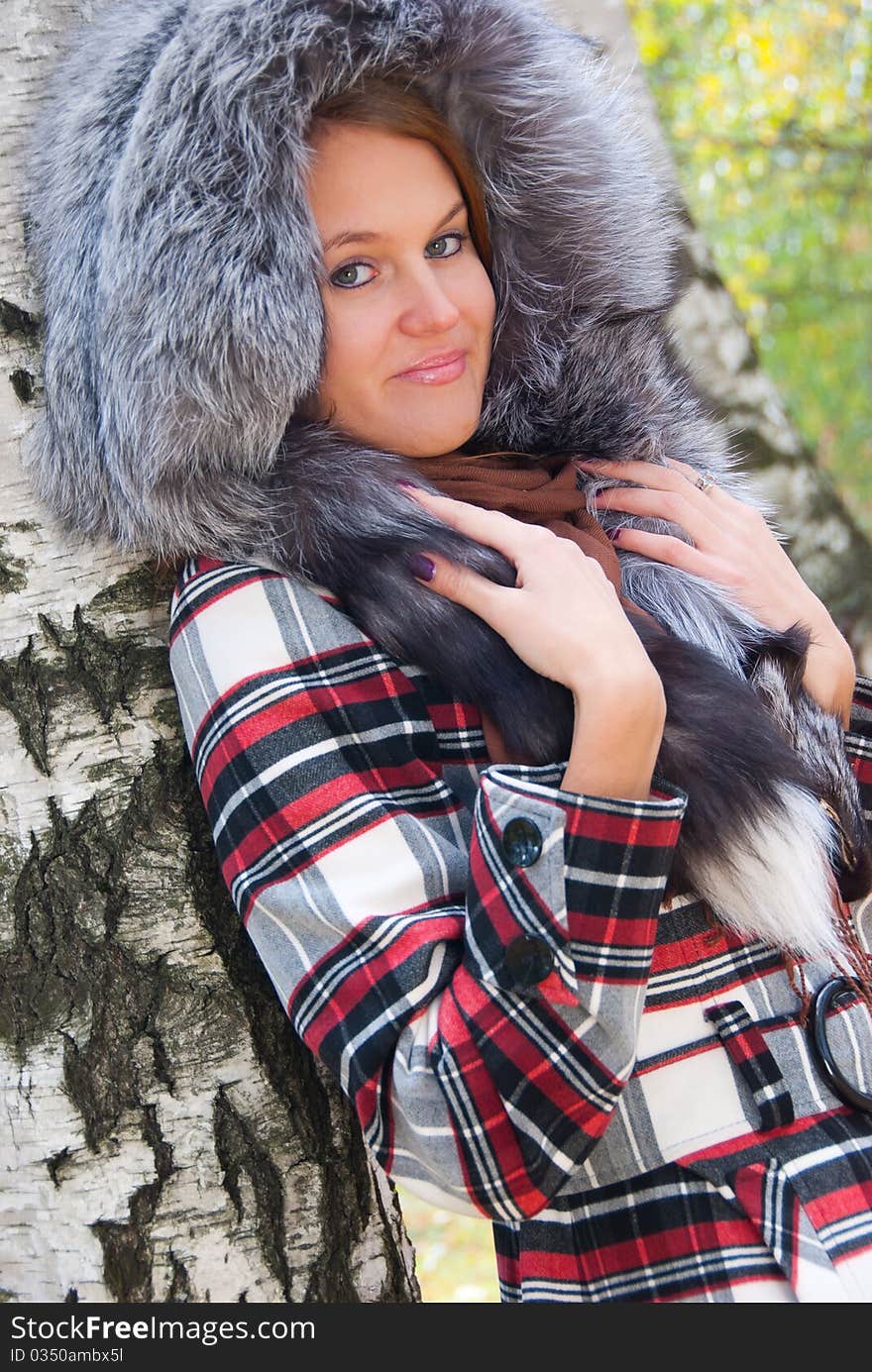 Portrait of a girl with a fur hood in the birch forest