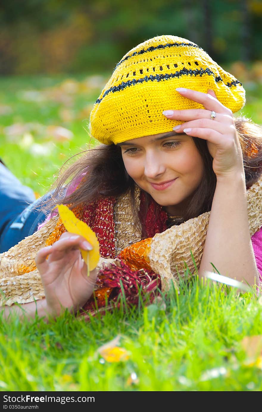 Beautiful girl lying on a grass with fallen leaves