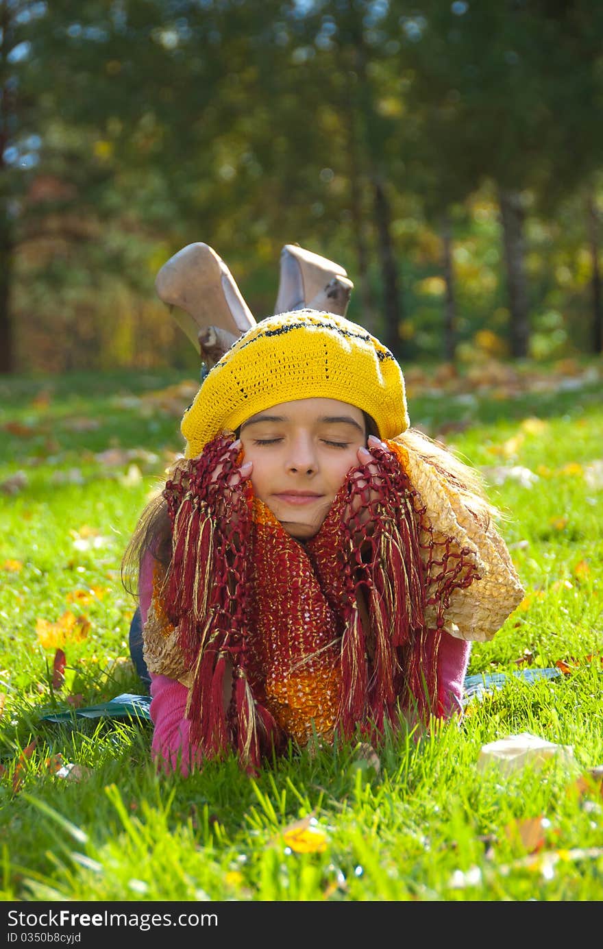 Beautiful girl lying on a grass with fallen maple leaves