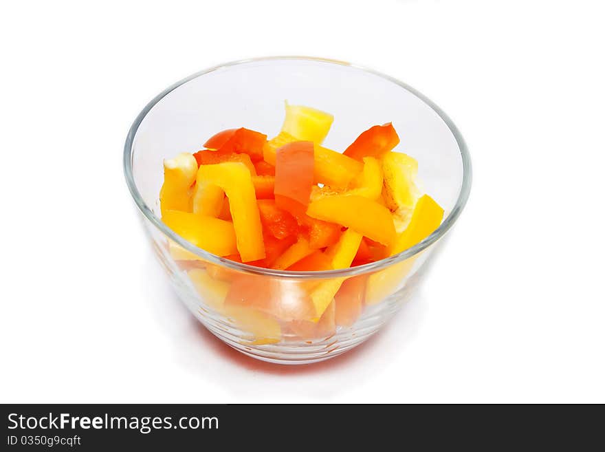 Slices of yellow pepper in a glass bowl on white background