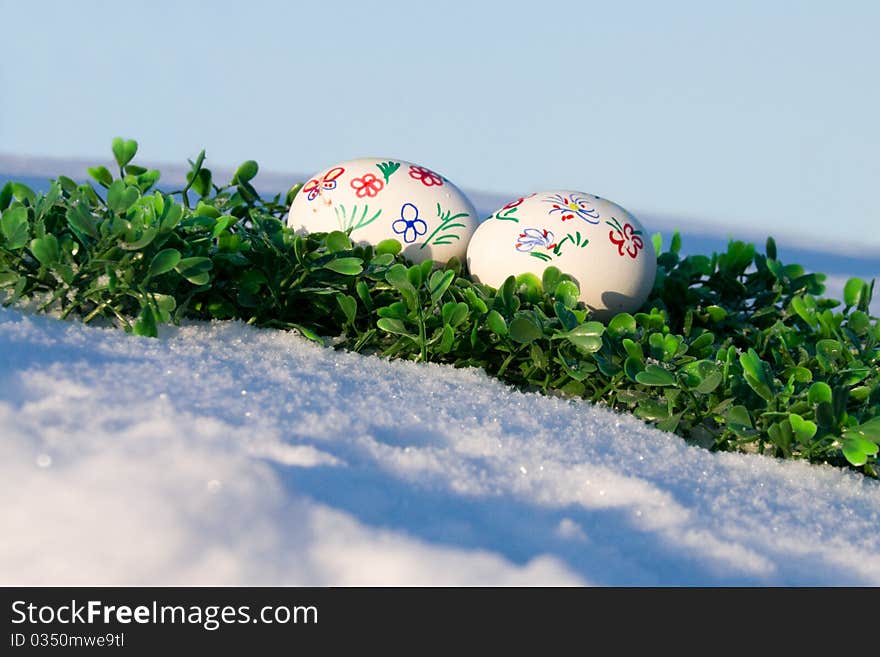 Easter eggs on a snowy hill on the skyline and the green