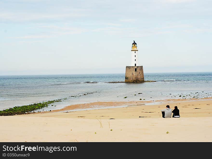 Lovers On A Beech With A Lighthouse