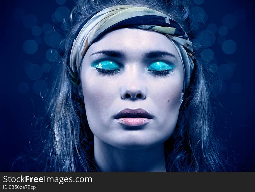 Beautiful young woman with blue make-up. Isolated on blue