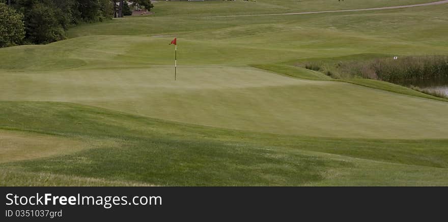 Red golf flag and pin on a green. Red golf flag and pin on a green