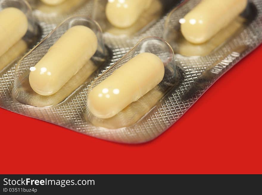 Pills in blister pack in red background, macro. Pills in blister pack in red background, macro