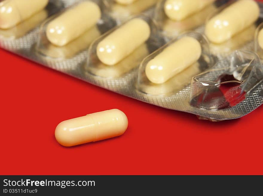 Pills in blister pack in red background, macro. Pills in blister pack in red background, macro