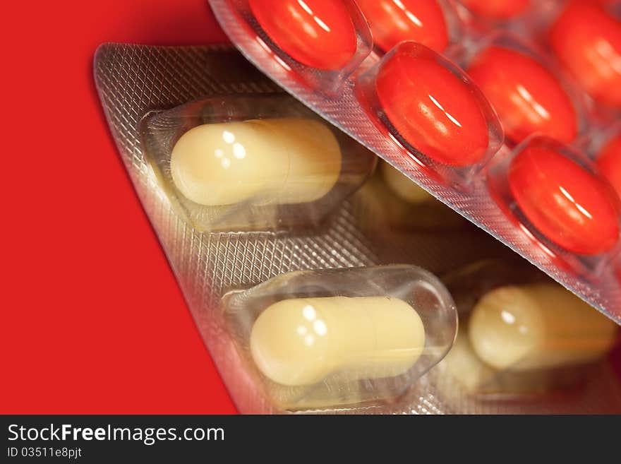 Pills in blister pack in red background, macro