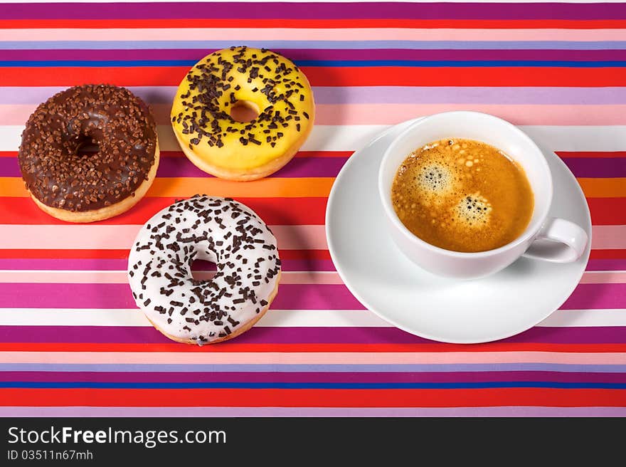 Donuts with cup of coffee on red tablecloth