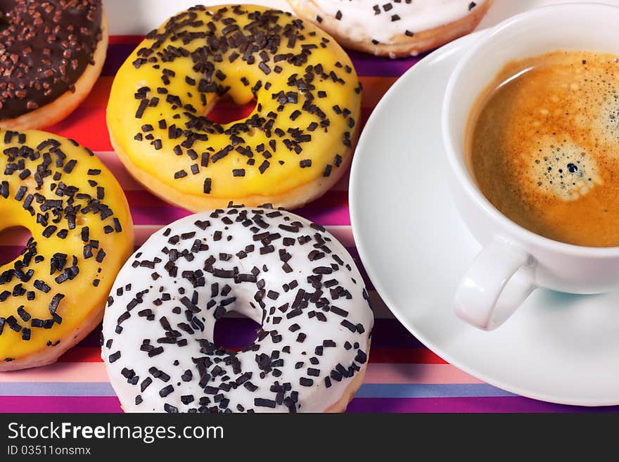 Donuts with cup of coffee on red tablecloth