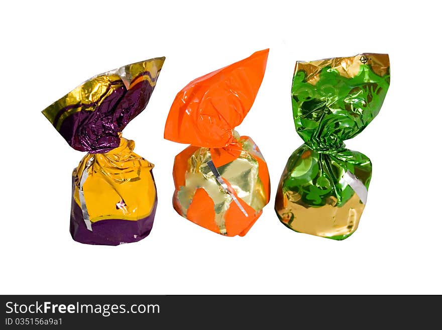 Three chocolates in a colored shiny packaging. white background. Three chocolates in a colored shiny packaging. white background.