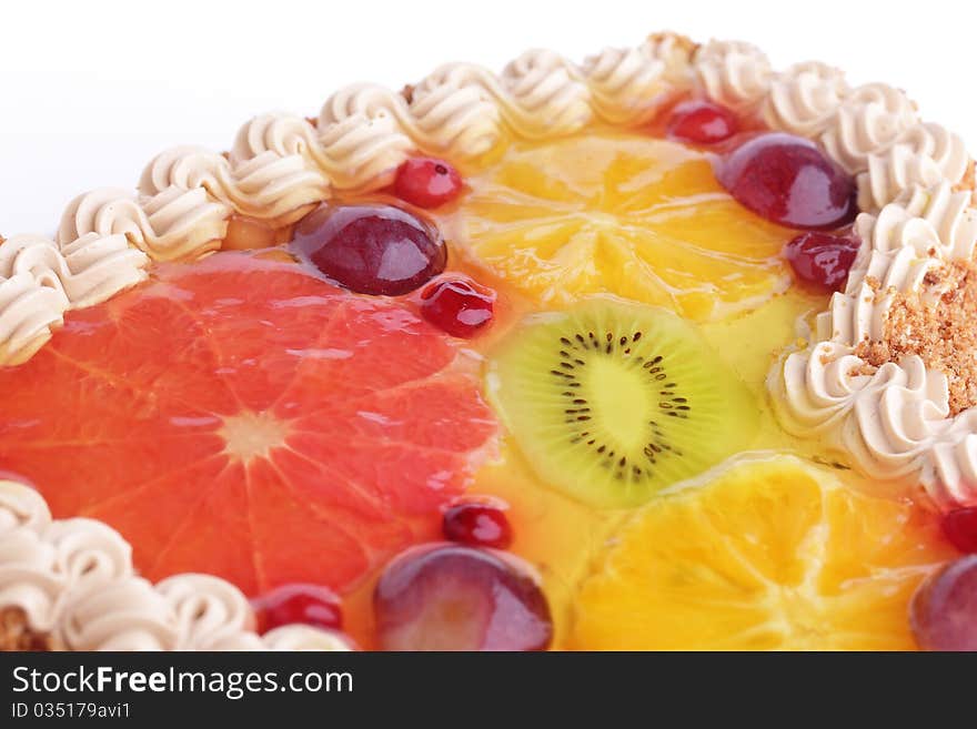 Delicious cake with whipped cream garnished with fruits (kiwi, grapefruit, orange, plum) in jelly isolated on white background. Delicious cake with whipped cream garnished with fruits (kiwi, grapefruit, orange, plum) in jelly isolated on white background